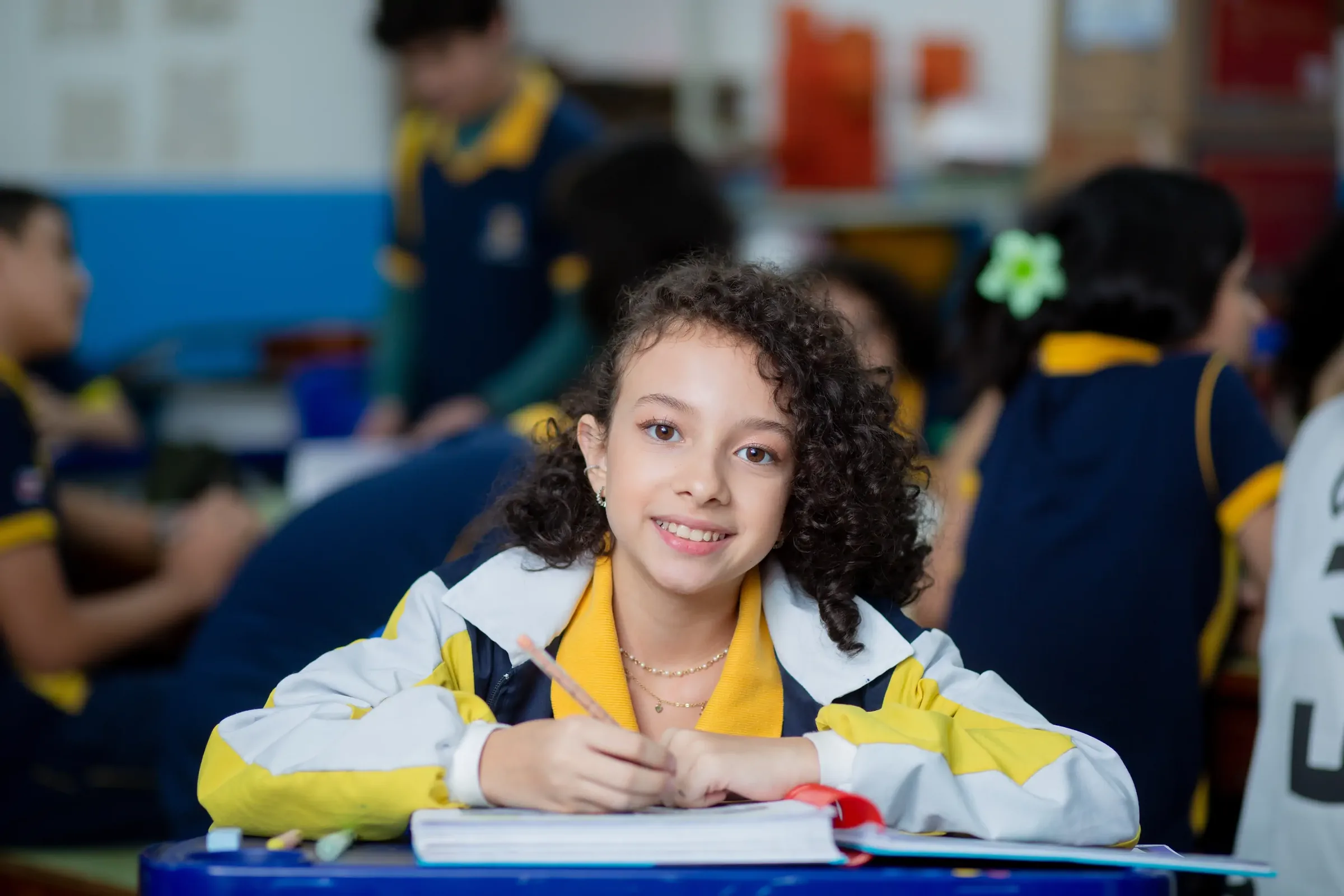 Aluna do Palas Atena sorrindo na carteira em sala de aula