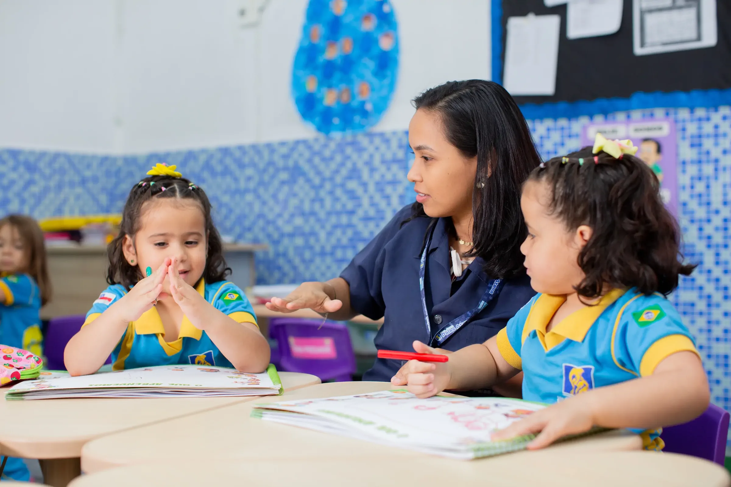 Professora do Palas Atena conversando com duas alunas da educação infantil