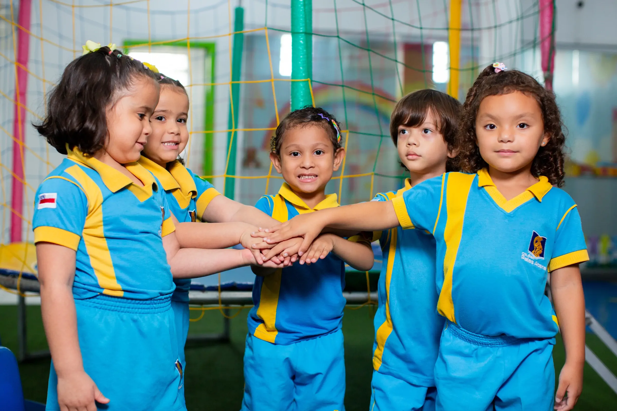 Crianças da educação infantil do Palas Atena de mãos unidas no playground