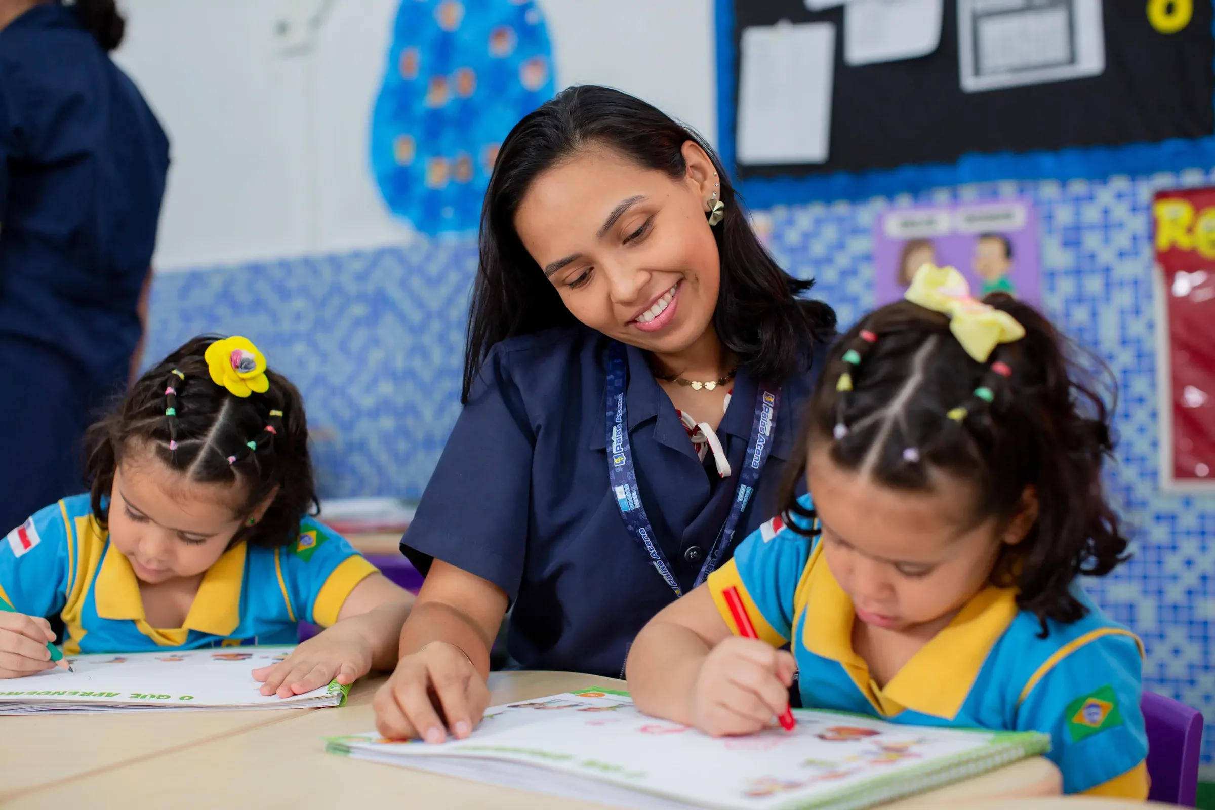 Professora do Palas Atena orientando uma aluna da educação infantil na escrita