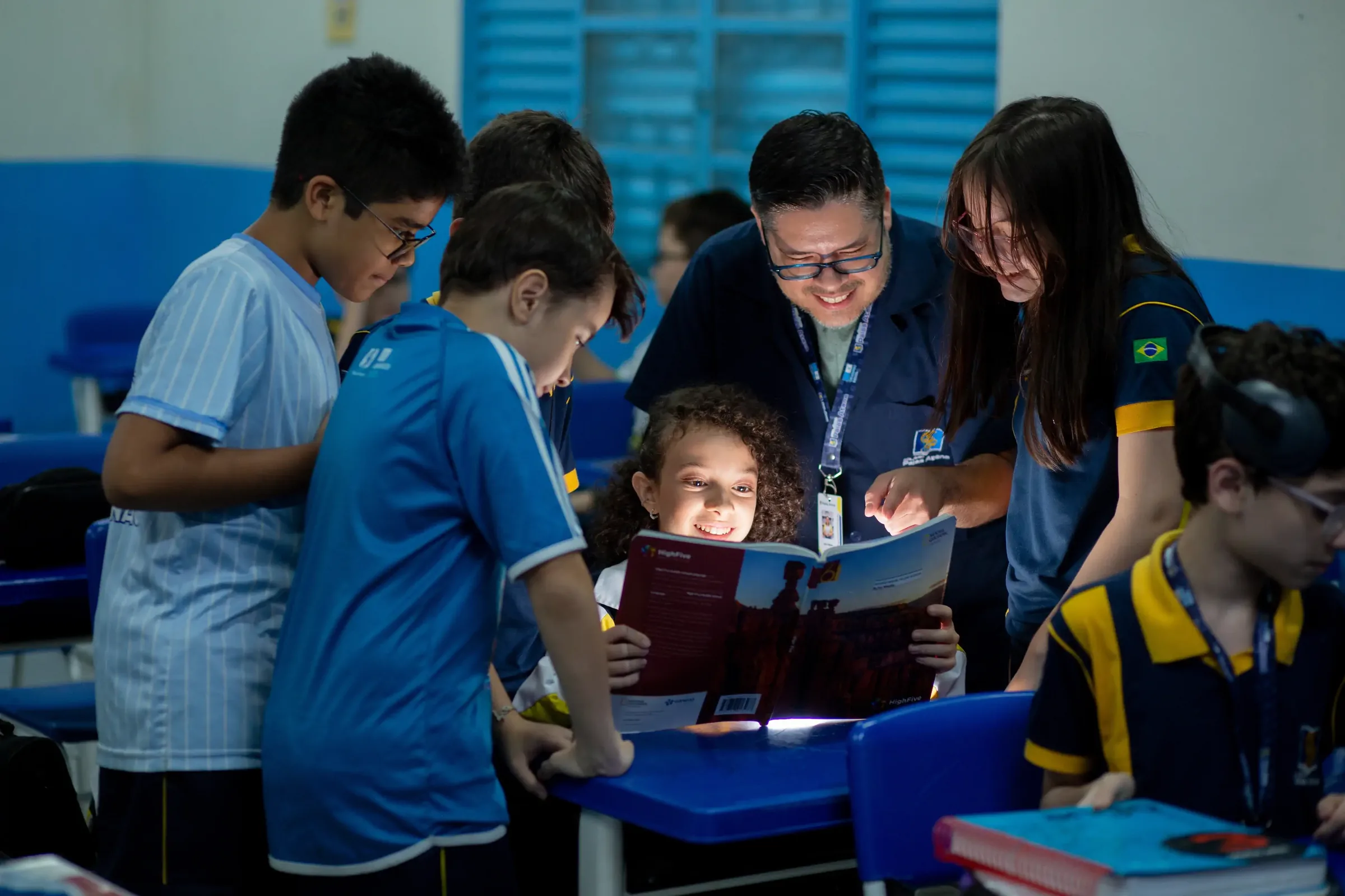 Professor e alunos do Palas Atena reunidos em torno de um livro