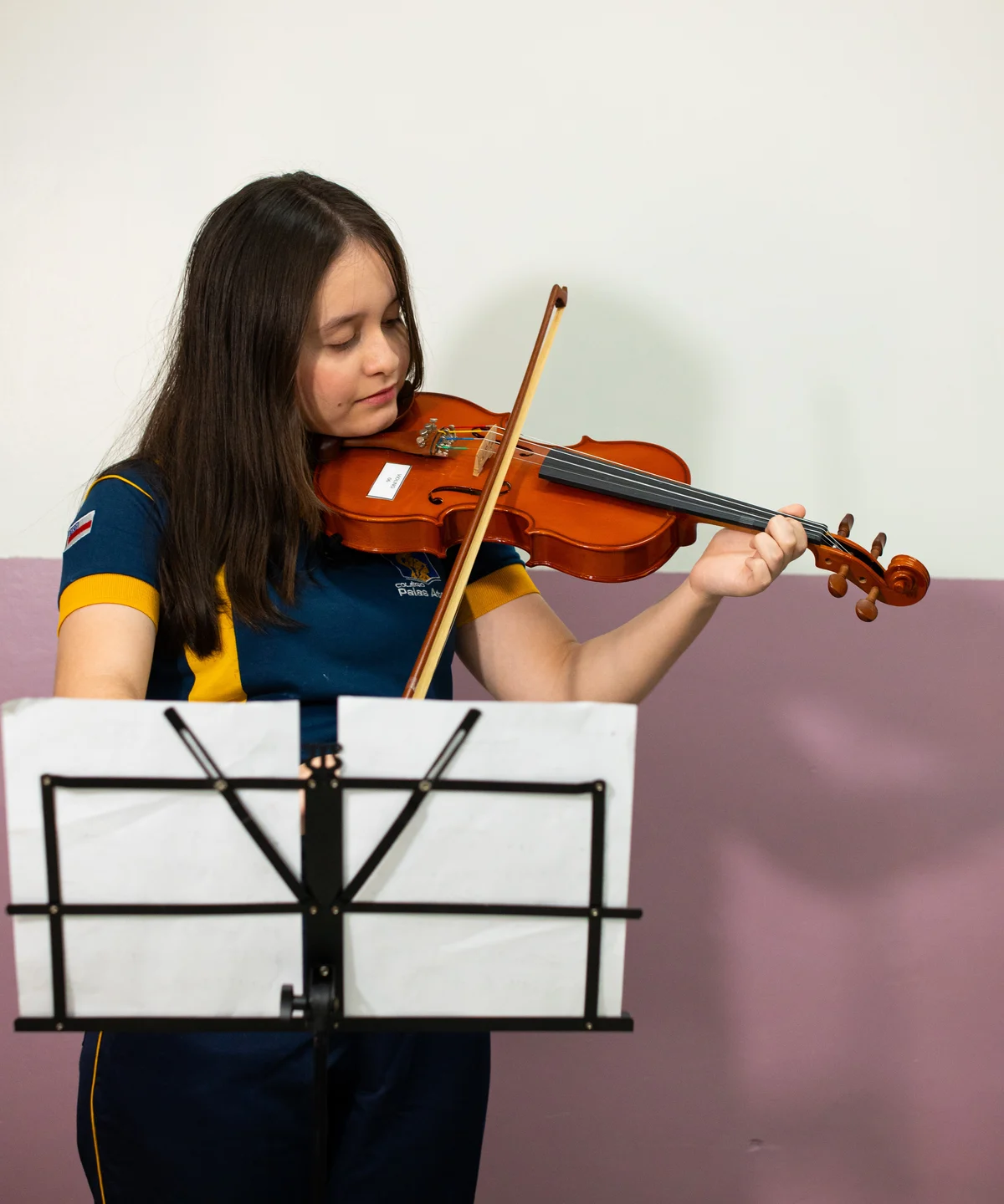 Aluna do Colégio Palas Atena praticando violino durante atividade musical