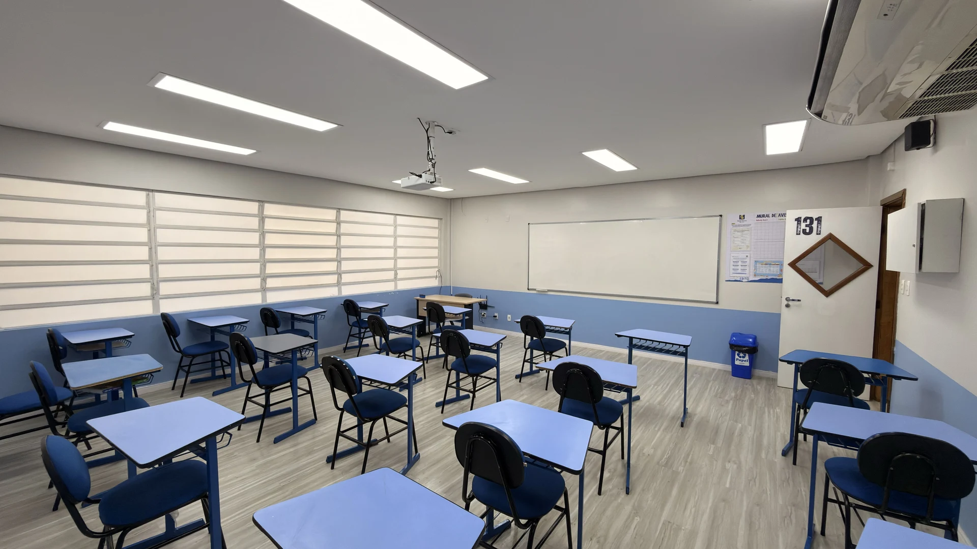 Sala de aula moderna com carteiras individuais e projetor no Colégio Palas Atena