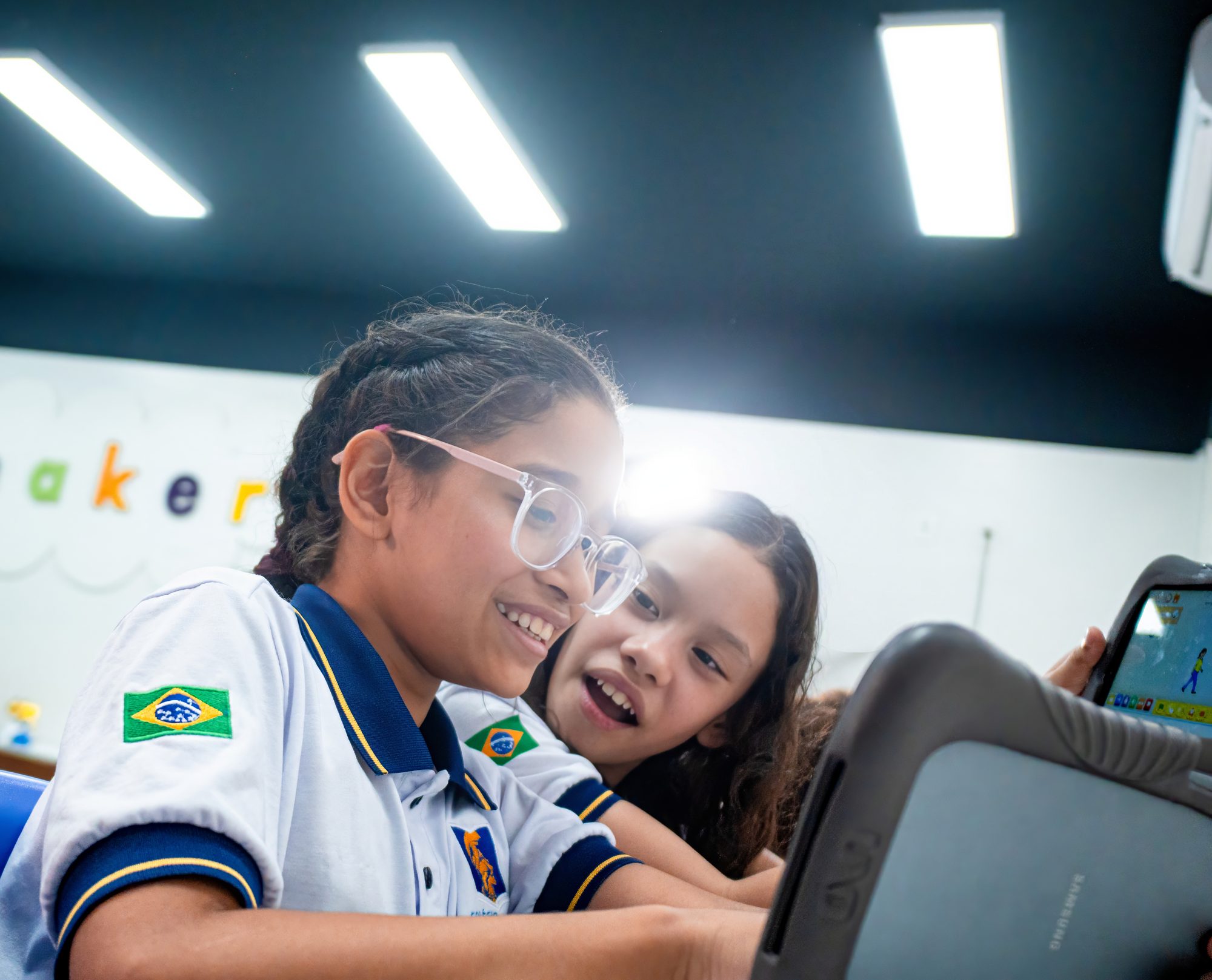Duas alunas do Palas Atena rindo diante de um tablet na sala maker