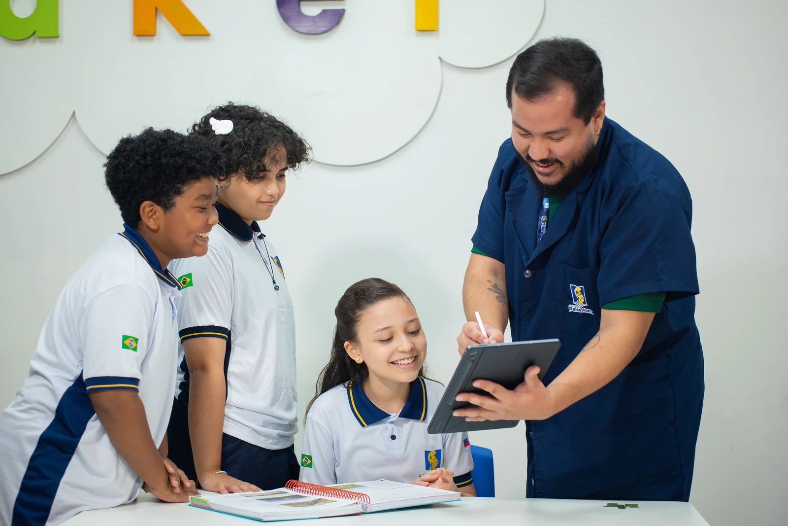 Professor do Tempo Integral orientando alunos com apoio de tablet no espaço maker